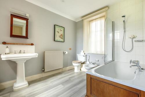 ein Badezimmer mit einer Badewanne, einem Waschbecken und einem WC in der Unterkunft Saham Grove Hall by Group Retreats in West Bradenham