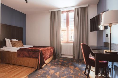 トロルヘッタンにあるClarion Collection Hotel Kung Oscarのベッドとデスクが備わるホテルルームです。