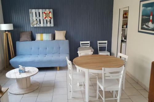un salon avec un canapé bleu, une table et des chaises dans l'établissement Duplex avec 3 chambres à 30m de la plage, à Merlimont