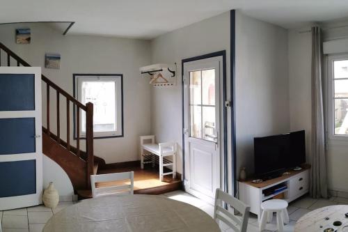 uma sala de estar com televisão e uma escadaria em Duplex avec 3 chambres à 30m de la plage em Merlimont