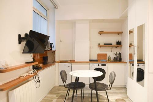 een keuken met een tafel en stoelen en een televisie bij Studio Cocoon Near Eiffel Tower in Parijs