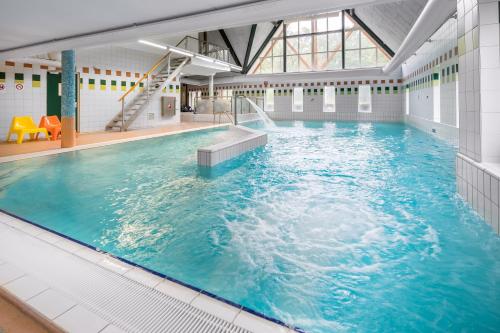 a large indoor swimming pool with blue water at Summio Landgoed Het Grote Zand in Hooghalen