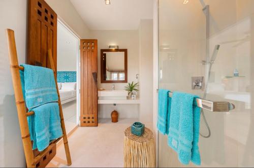 a bathroom with blue towels and a shower at Baan Fhan Talay in Laem Set Beach