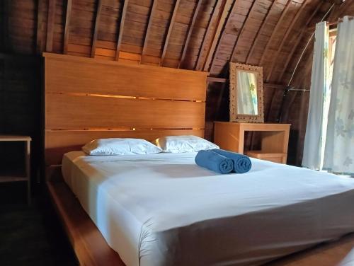 a bedroom with a large white bed with a wooden headboard at Villa Lumbung Petanahan in Jembrana