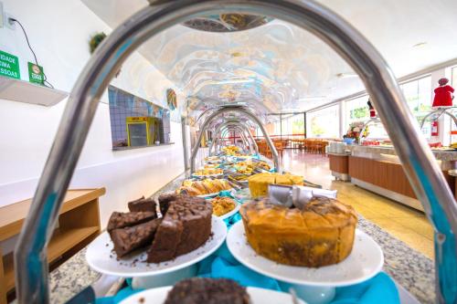 une vitrine avec des gâteaux et d'autres desserts sur des assiettes dans l'établissement DiRoma Fiori Hotel - BVTUR, à Caldas Novas