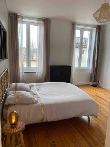 une chambre avec un grand lit et deux fenêtres dans l'établissement Chez Julie, à Castres
