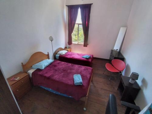 Cette petite chambre comprend 2 lits et une fenêtre. dans l'établissement República Hostel, à Valparaíso