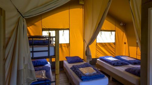 a room with three bunk beds in a yellow tent at Camping De Boerinn in Kamerik