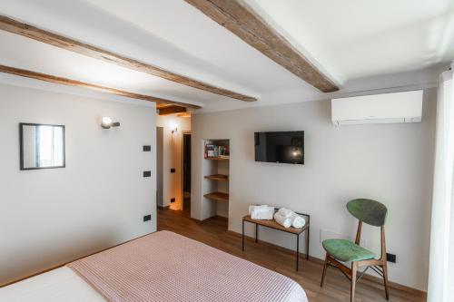 um quarto com uma cama e uma cadeira e uma televisão em Casa Cicetta em San Marino