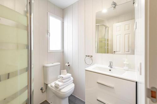 a white bathroom with a toilet and a sink at Apartamentos JAP Preciados in Madrid