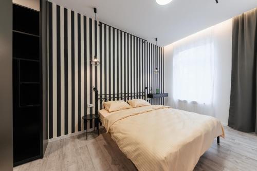 a bedroom with a bed with a black and white striped wall at Luxury Apartments Laborca in Uzhhorod