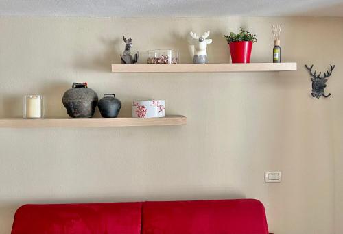 Alpine Studio with Garage في Breuil: غرفة معيشة مع رفوف مع مزهريات وأريكة حمراء