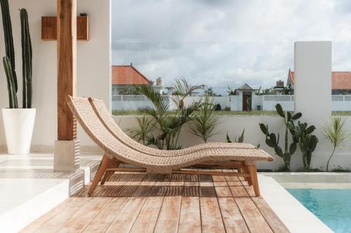 a rattan chair sitting on a deck next to a pool at Villa FES 2 Bedrooms Private Villa 5mins Beach in Munggu