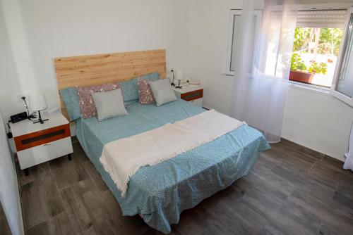 a bedroom with a bed with a blue comforter and two windows at EL MIRADOR in Jaén