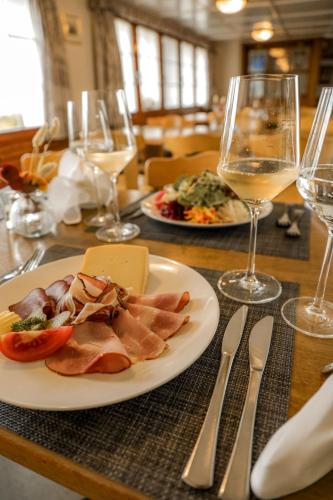 a table with a plate of food and glasses of wine at Hotel und Gasthaus Bad Gonten in Gonten