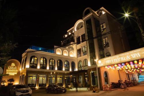 SALA HOTEL HUE في هوى: مبنى فيه سيارات تقف امامه ليلا
