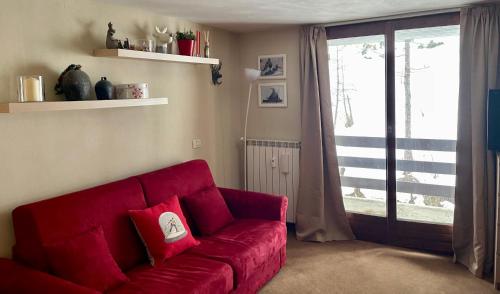a red couch in a living room with a sliding glass door at Alpine Studio with Garage in Breuil
