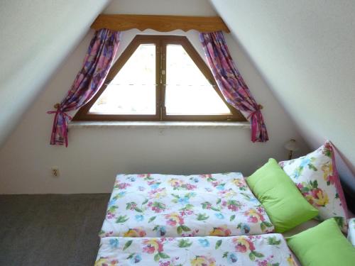 a small attic room with a bed and a window at Ferienhaus mit Kamin , Terrasse und Aussensauna in Pöhla