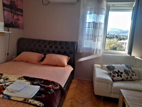 a bedroom with a bed and a couch and a window at Stankovic Apartman in Vranje