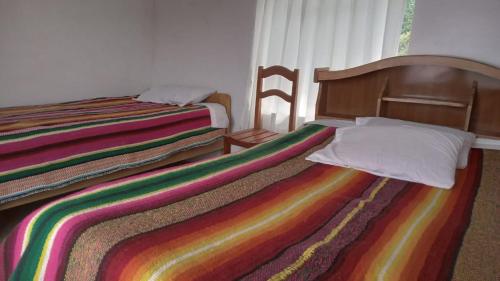 a bedroom with two beds with a rainbow blanket at Wiñay Wasi Occosuyo in Amantani