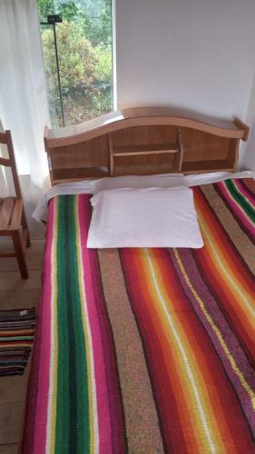 Ocosuyo的住宿－Wiñay Wasi Occosuyo，一张带多彩床罩的床,床边是床边