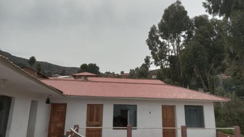 una pequeña casa blanca con techo rojo en Wiñay Wasi Occosuyo en Ocosuyo