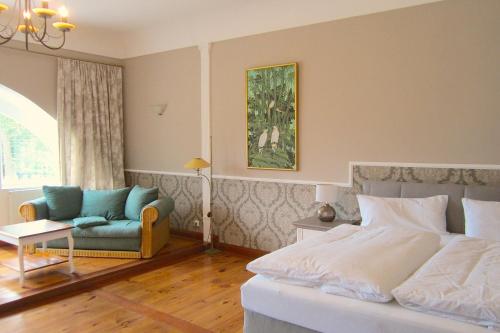 une chambre avec un lit, un canapé et une chaise dans l'établissement Landhotel Gut Zarrentin, à Gransebieth