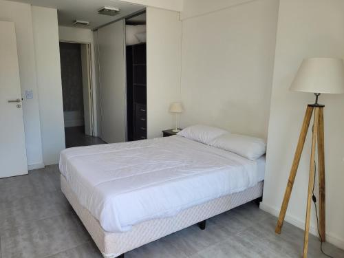 1 dormitorio con cama blanca y lámpara de pie en APART PARAGUAY Y FITZ ROY 3 en Buenos Aires