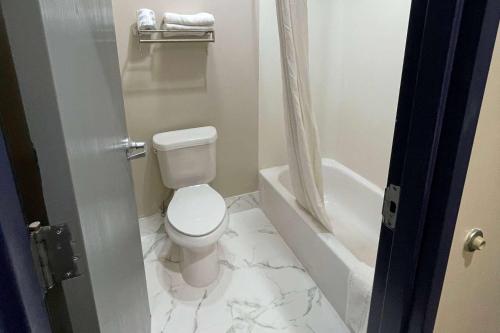 a white bathroom with a toilet and a bath tub at Baymont by Wyndham Adairsville in Adairsville
