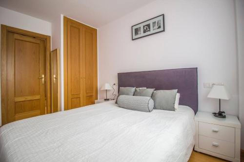 een slaapkamer met een groot wit bed met een paars hoofdeinde bij 1. APT cerca a pistas de esquí y la Vall d'Incles in Soldeu
