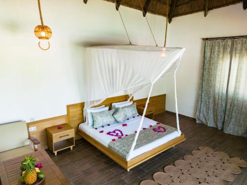 a bedroom with a bed with a mosquito net at Turkuaz Beach Zanzibar in Kumba Urembo