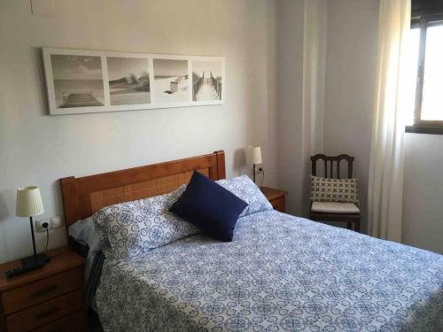1 dormitorio con 1 cama con edredón azul y silla en Piso acogedor con vistas al mar, en La Torre