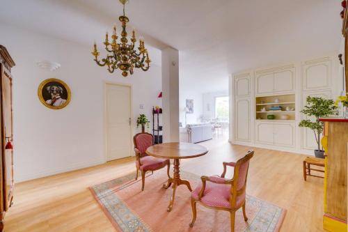 una sala da pranzo con tavolo, sedie e lampadario pendente di Lovely apartment with exceptional terrace a Bordeaux