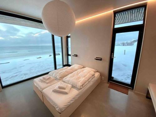 um quarto com uma cama e uma grande janela em Exclusive Beach House Ramberg em Ramberg