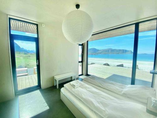 a bedroom with a bed and a large window at Exclusive Beach House Ramberg - Your Private Oasis in Ramberg