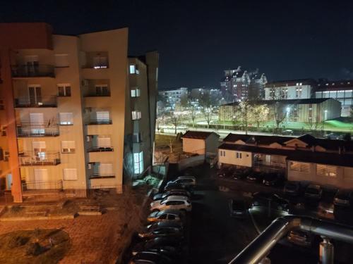 a city at night with cars parked in a parking lot at Ena Apartment in Vranje