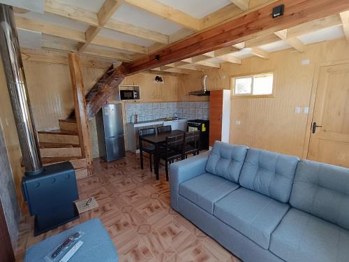 sala de estar con sofá azul y cocina en Cabañas Hornopirén, en Hornopirén