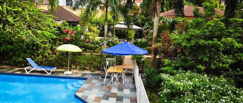 a pool with a blue umbrella and a table and chairs at Villa Oasis Abidjan in Abidjan