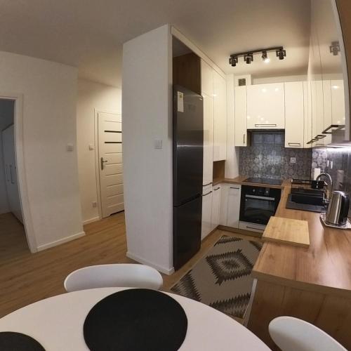 uma cozinha com armários brancos e um frigorífico preto em Apartament Sando em Sandomierz