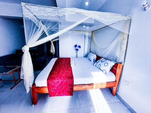 een slaapkamer met een hemelbed en een rode deken bij Studio at Kisimani Heights Apartment. in Mombasa