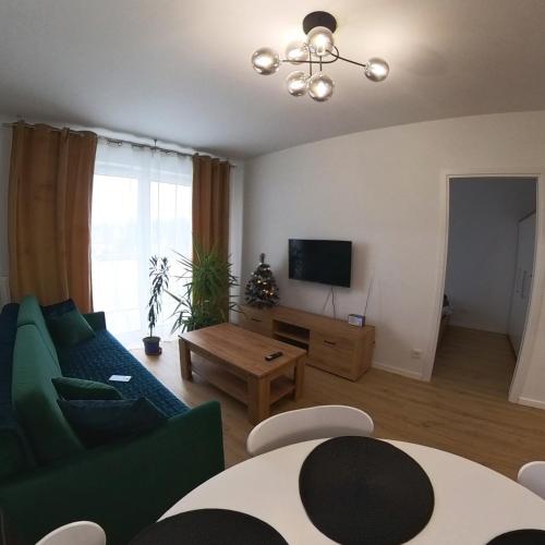 uma sala de estar com um sofá verde e uma televisão em Apartament Sando em Sandomierz