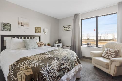 a bedroom with a bed and a chair and a window at Restauparc Motel in Casselman
