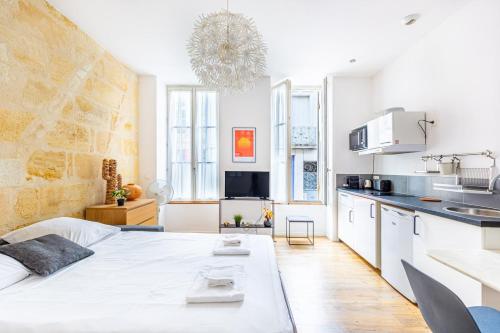 - une chambre blanche avec un grand lit et une cuisine dans l'établissement Appartement charmant Bordeaux centre, à Bordeaux