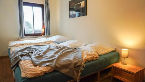 niepościelone łóżko w pokoju z oknem w obiekcie Apartment mit Herz im Harz w mieście Meisdorf