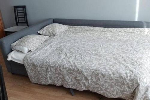 a bed with a gray comforter and pillows on it at 50m2 Apartment FREE Parking and Laundry, 20min to Center in Espoo