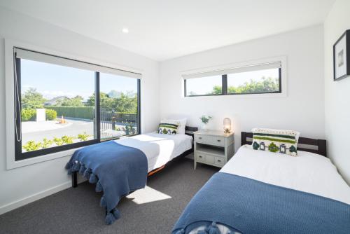 a bedroom with two beds and a large window at Vinebox on Wilson in Martinborough 