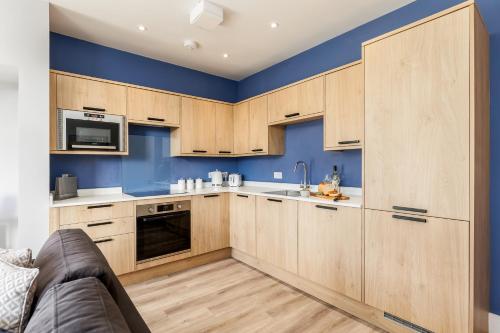 a kitchen with wooden cabinets and blue walls at Tower House Apartments in Bournemouth