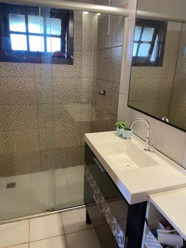 a bathroom with a glass shower and a sink at Chalé Rústico com piscina in São Gabriel