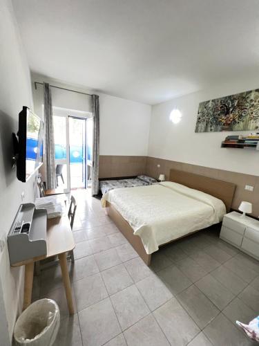 Schlafzimmer mit einem Bett, einem Schreibtisch und einem TV in der Unterkunft Coccinella in Sabaudia