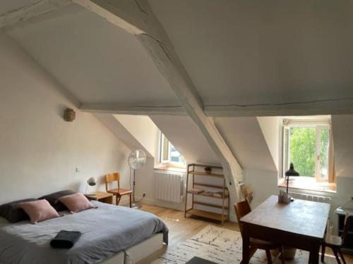 - une chambre mansardée avec un lit et une table dans l'établissement Grande chambre indépendante, charme, calme sur jardin, Nantes centre, accès privé par escalier de l'immeuble, sdb & wc privés, 10 minutes gare et palais des congrès, à Nantes